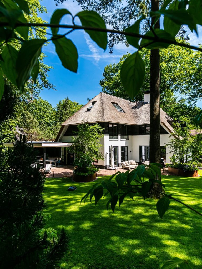 Achterzijde zicht vanuit de tuin rietgedekte villa gebouwd door Lichtenberg Exclusieve Villabouw.