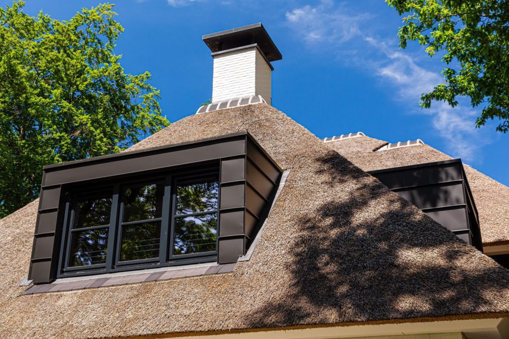 Zwarte aluminium dakkapel bij rietgedekte villa gebouwd door Lichtenberg Exclusieve Villabouw