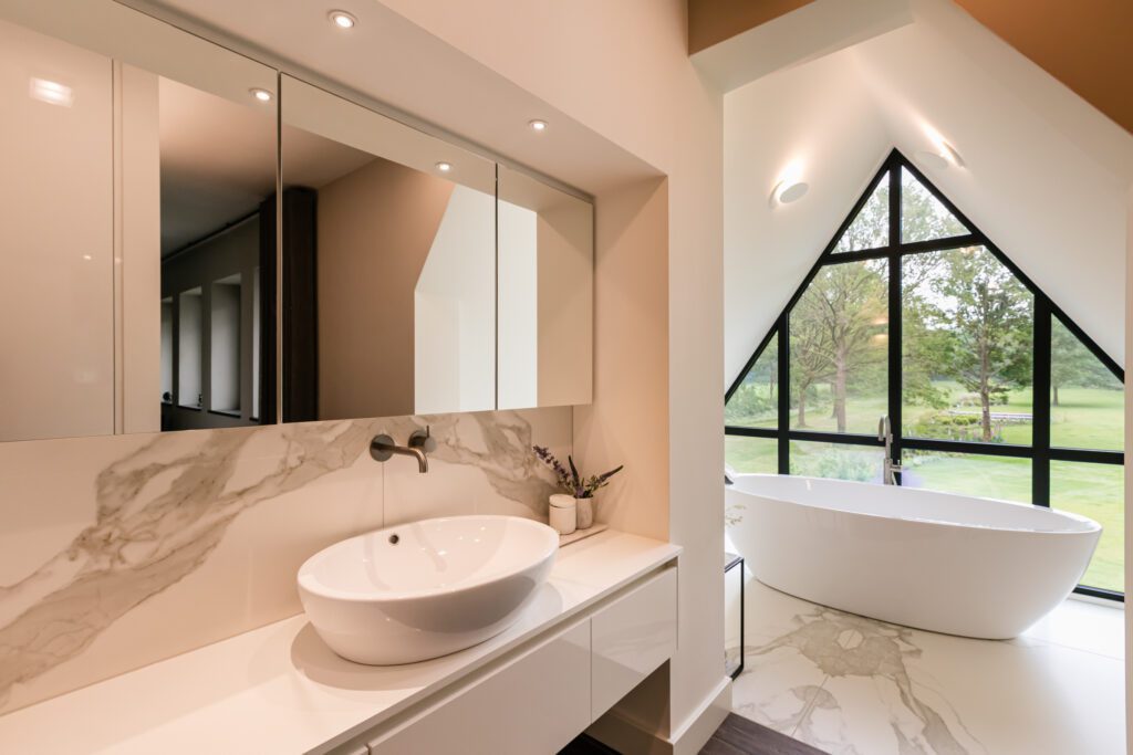 Moderne badkamer met vrijstaand bad bij groot raam. Lichtenberg Villabouw.